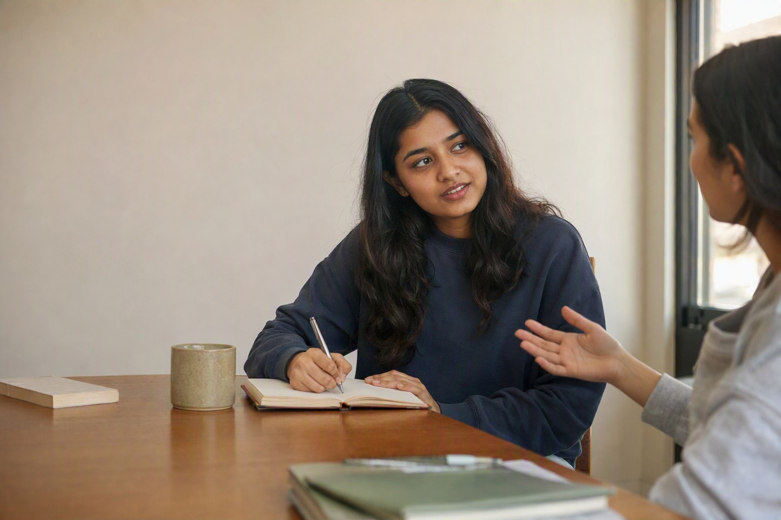 An open journal with a pen next to a phone on a voice call, the two ways of processing a difficult day: writing it down or talking it through.
